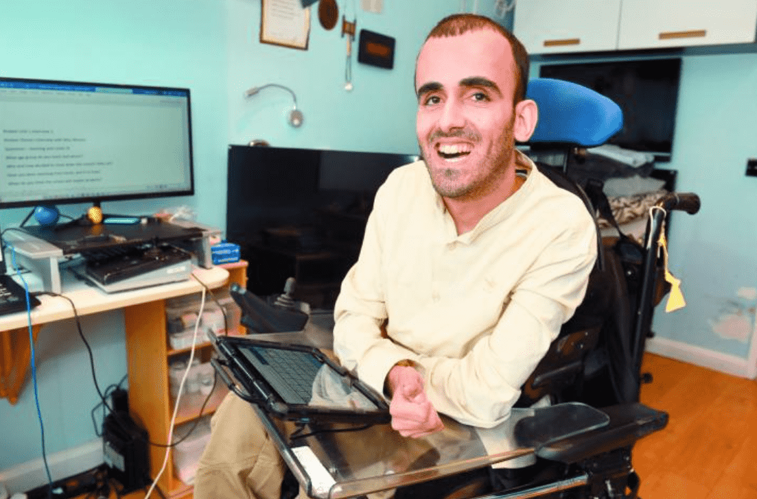 A person in a wheelchair holding a tablet

Description automatically generated