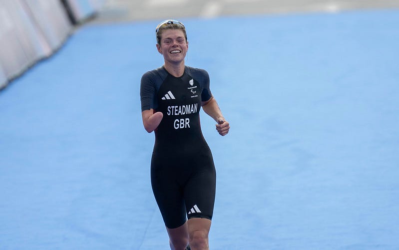Lauren Steadman mid run during the paratriathlon smiling wearing a GB kit.