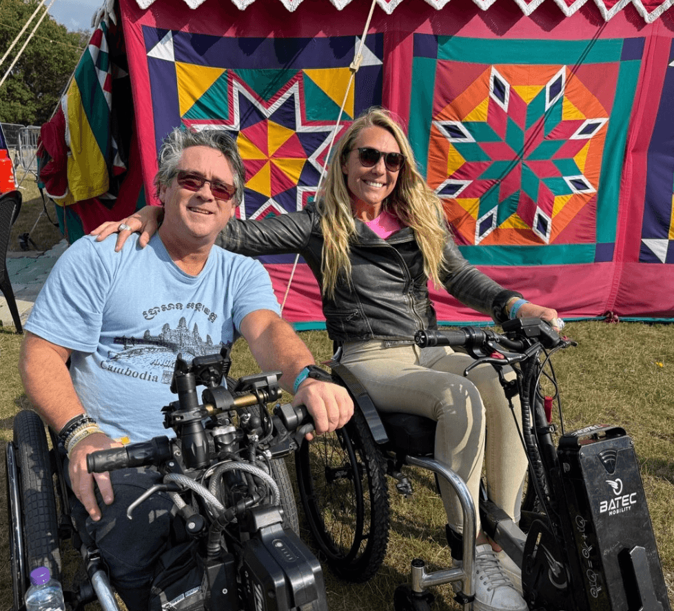 Sophie Morgan interviewing Grant Logan both on trikes in front of a brightly patterned festival tent