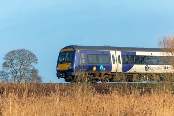 A Northern Train in motion traveling through the countryside on a sunny day